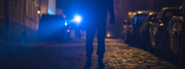 The man with a flashlight stand on wet road. Evening night time
