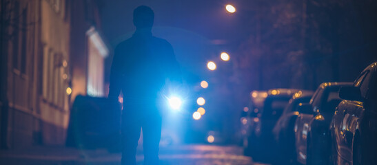 The man with a flashlight inspect the street. Evening night time - obrazy, fototapety, plakaty