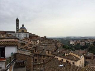 Fototapeta na wymiar SIENA, ITALY. Panorama view of Siena medieval buildings. Evening, cloudy sky, Tuscany hills on a background, tile rooftop. Date of photo is 01.10.2015