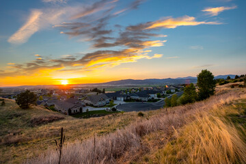 A setting sun during mid summer showing the cities of Spokane, Spokane Valley, and Liberty Lake Washington, USA, from a hilltop overlooking homes.