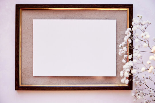 Brown frame mockup on vintage surface. Vintage frame with gypsophila. Beige background, Scandinavian interior. Top view. Place for advertising, thank you or wishing.