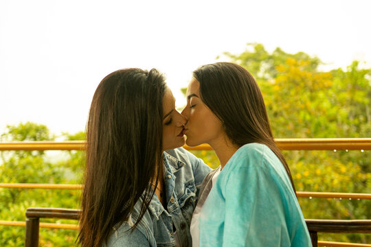 Pareja de j&oacute;venes lesbianas bes&aacute;ndose con vista a la naturaleza 