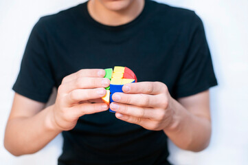 The young boy holds a puzzle toy in his hands and tries to fold it correctly by color, the guy develops his brain, the ability to think