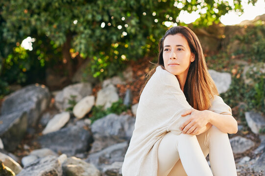 Outdoor portrait of beautiful middle age woman relaxing in nature, wearing light beige clothing