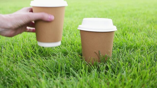 Biodegradable disposable cups of coffee on green grass.