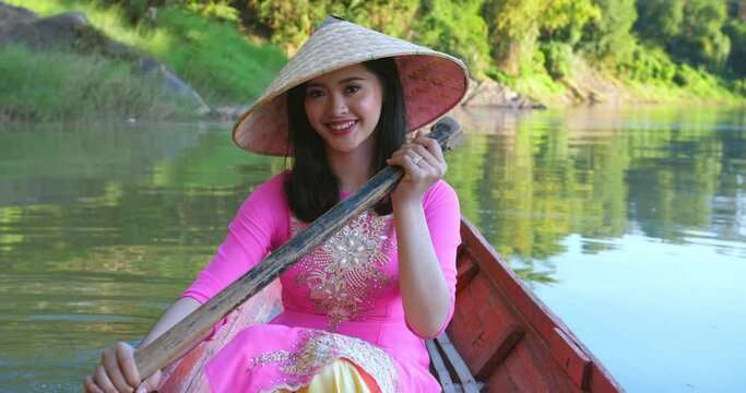 Vietnamese Woman Rowing A Boat And Looking At Camera
