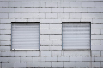Obraz na płótnie Canvas window on a brick wall, white wall with two closed shutters, both window with roll able jalousie, no person