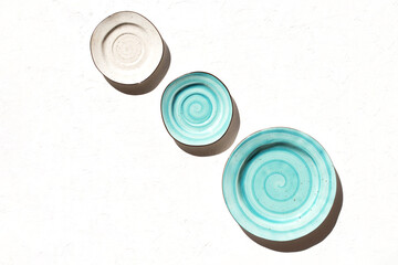 Three aquamarine and light beige plates on white textured background