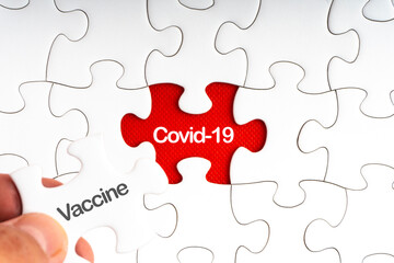Fototapeta premium COVID-19 VACCINE text with jigsaw puzzle on red background. Covid-19 and Coronavirus Concept