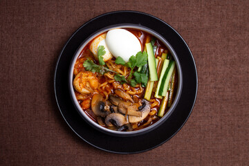 top view spicy ramen with mushrooms, eggs and seafood and cucumbers