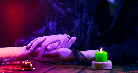 The witch is a fortune teller who holds her hand during a session under neon light. Psychic...