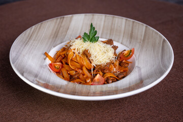 appetizing pasta with beef, tomatoes and hard cheese in a plate.
