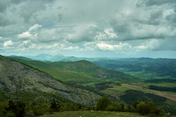 Fototapeta na wymiar The lush green Kraishte mountain ranges in Bulgaria, Europe, in spring, against a dramatic cloud backdrop, as seen from the Lubash peak slopes.
