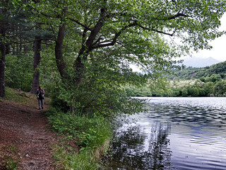 Fototapeta premium a woman walks along a footpath around an alpine lake