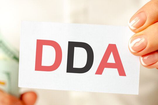 On the table are bills, a bundle of dollars and a sign on which it is written - dda, concept