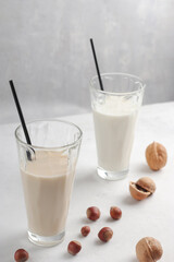 Health concept. Natural breakfast. In glass glasses, nut milk on a light background. Organic vegetarian drinks. Vertical position