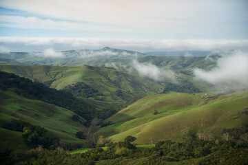 looking down on green mountain landscape with clouds. Shot from above the clouds