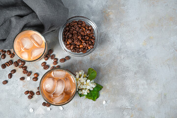 Iced coffee and coffee beans on a gray background.