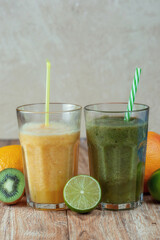 Tall glass with kiwi and spinach smoothie surrounded by fruits on a wooden table