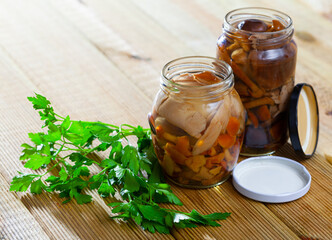 Glass jars with mixed marinated mushrooms and fresh greens. Homemade pickles..