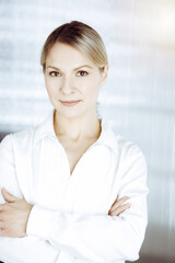 Fototapeta premium Friendly adult business woman standing straight. Business headshot or portrait in sunny office