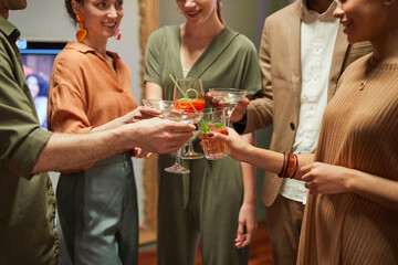 Close up of diverse group of friends clinking glasses while toasting at indoor party, copy space