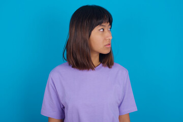 Close up side profile photo young beautiful asian woman wearing purple t-shirt against blue wall...