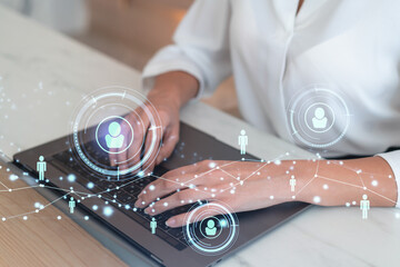Fototapeta premium HR woman specialist is typing the keyboard in the internet to find the best candidates to create international network in recruitment process. Formal wear. Social media hologram icons.