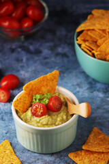 Homemade guacamole with corn chips and cherry tomatoes