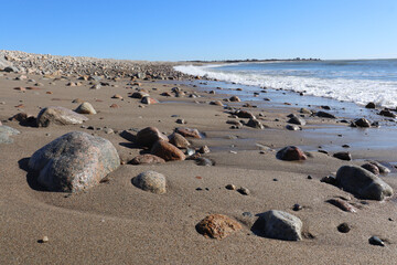 Variety of colorful orange, brown, and gray rocks on the wet sand on the beach