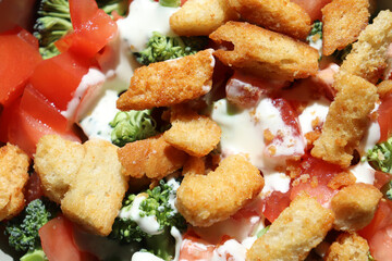 Closeup of fresh salad with green broccoli, red tomatos, toasted croutons, and white ranch dressing