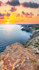 Dramatic sunset at cape Fiolent with bushes grass and rocks at foreground.