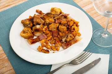 Delicious meat dish of roast pork and stewed beans on white plate