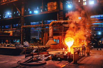 Pouring molten metal into mold from ladle container in foundry metallurgical factory workshop, iron...