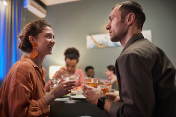 Side view portrait of young people chatting while enjoying dinner party with friends