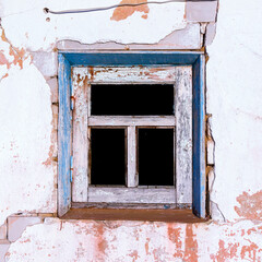a small window with a wooden frame in an old cracked wall