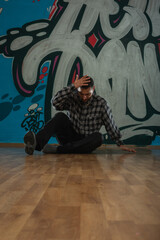 Trendy young man dancer dancing in front of graffiti.