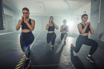 Group of sportswomen in sportswear doing lunge exercise at the gym with their left leg