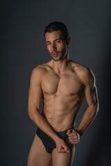 Fototapeta premium Sensual close-up portrait of a handsome male with bare torso posing in black undeware on isolated background