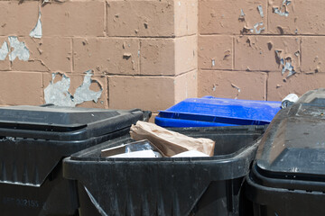 garbage bins in the park near a painted wall made of blocks