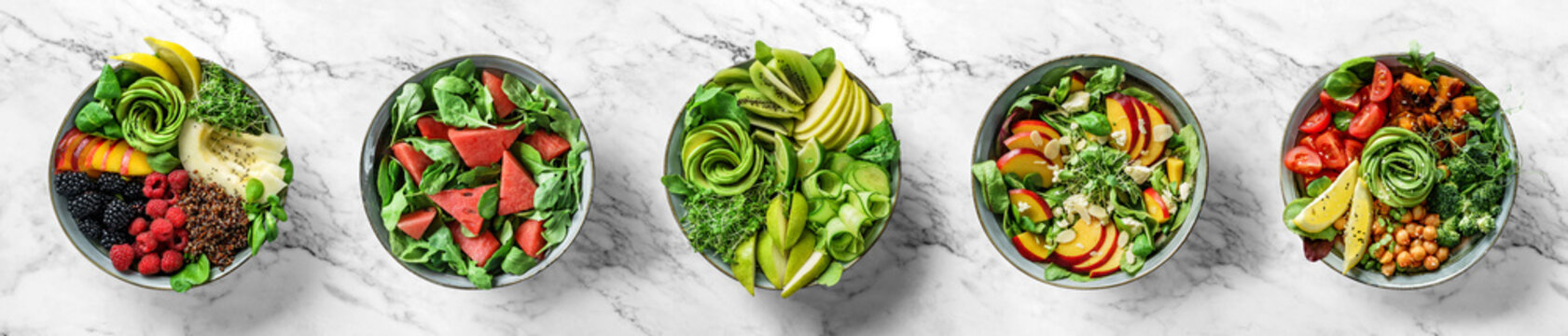 Five summer salads with fruits, berries, quinoa, micro greens, avocado, vegetables on light marble background with tropical leaves. Healthy food, clean eating, Buddha bowl salad, detox, top view