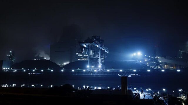 Crane of Coal fired power station on the edge of river works in the blue industrial light of the night