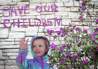 pretty little caucasian girl smiling and waving under a sign saying "save the children"