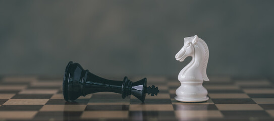 Chess Pieces on Board for Game and Strategy concept. White Chess Knight among lying down black king...
