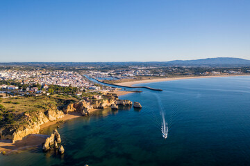 Fototapeta premium Camilo Beach at sunrise. Lagos, Algarve - Portugal. Portuguese southern golden coast cliffs. Sunny day aerial view.