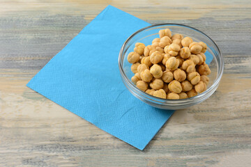 Turkish salted roasted chickpeas in glass snack bowl with blue napkin on table