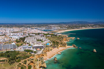 Fototapeta na wymiar Dona Ana Beach in Lagos, Algarve - Portugal. Portuguese southern golden coast cliffs. Aerial view with city in the background.