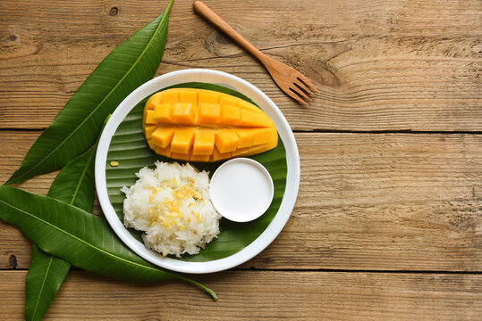 Asian Thai dessert sweet mango peel and sliced on white plate and fresh leaves mango, Ripe mango rice cooked with coconut milk, Sticky rice summer tropical fruit food