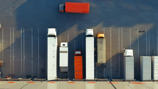 Semi-trailers trucks stand at warehouse ramps for load and unload goods in a large logistics park. Aerial top down view