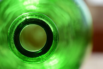 Close-up of an green glass bottle, illuminated by sunlight from behind. A look inside the large...